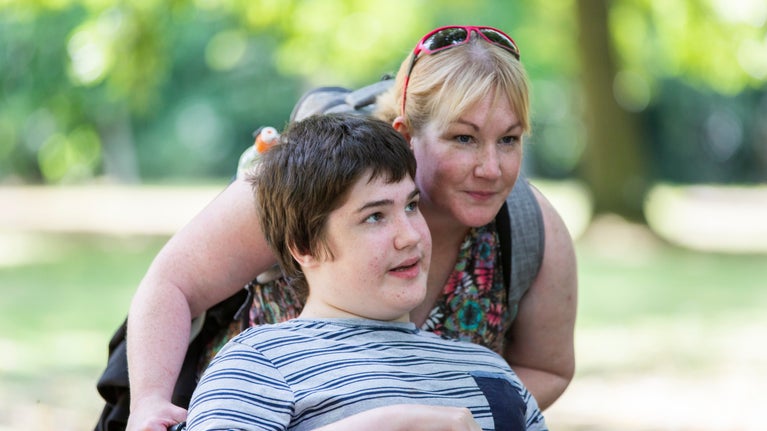 A woman and a boy in a wheelchair in parkland at Nostell, Yorkshire